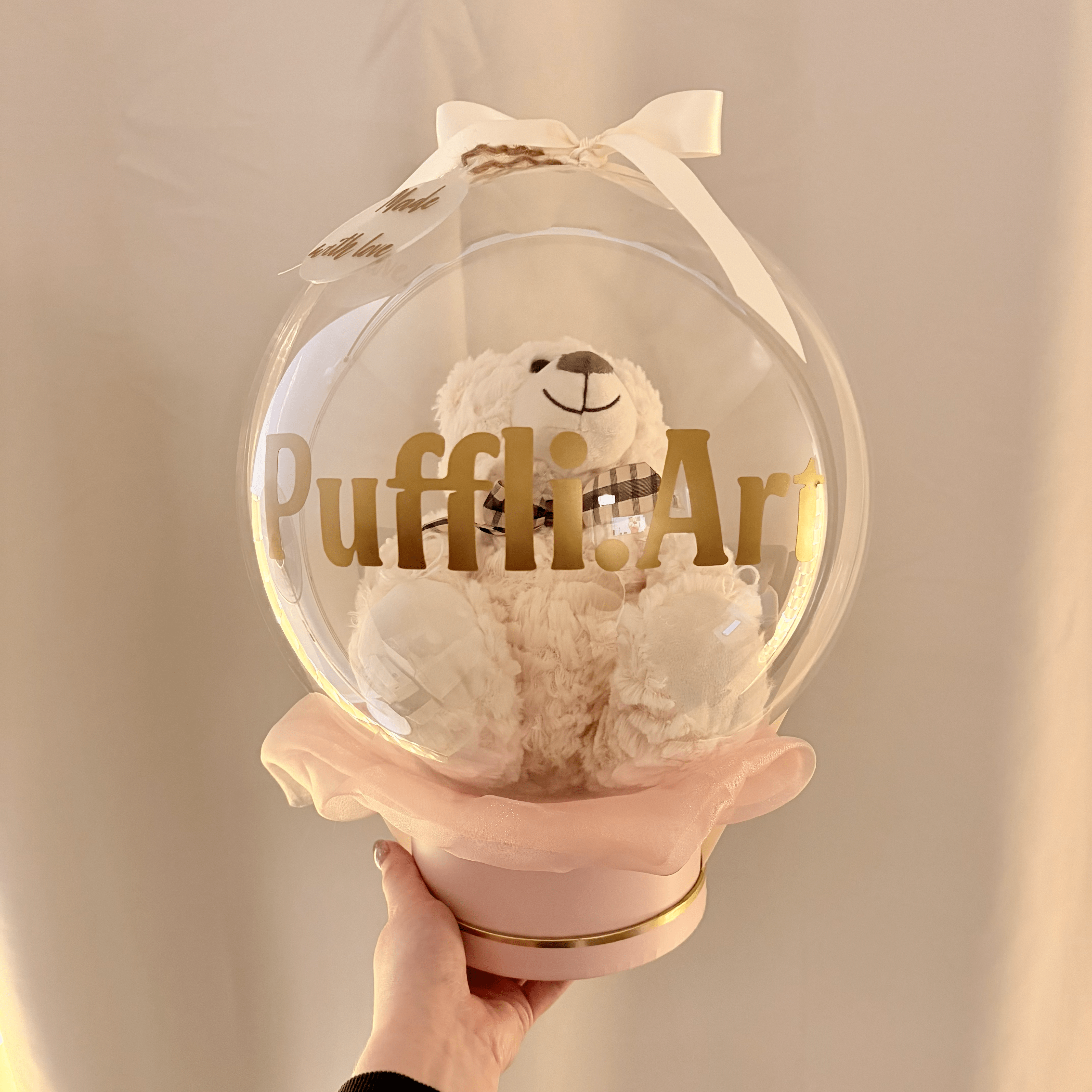 Teddy bear and sweets arranged within a transparent balloon basket