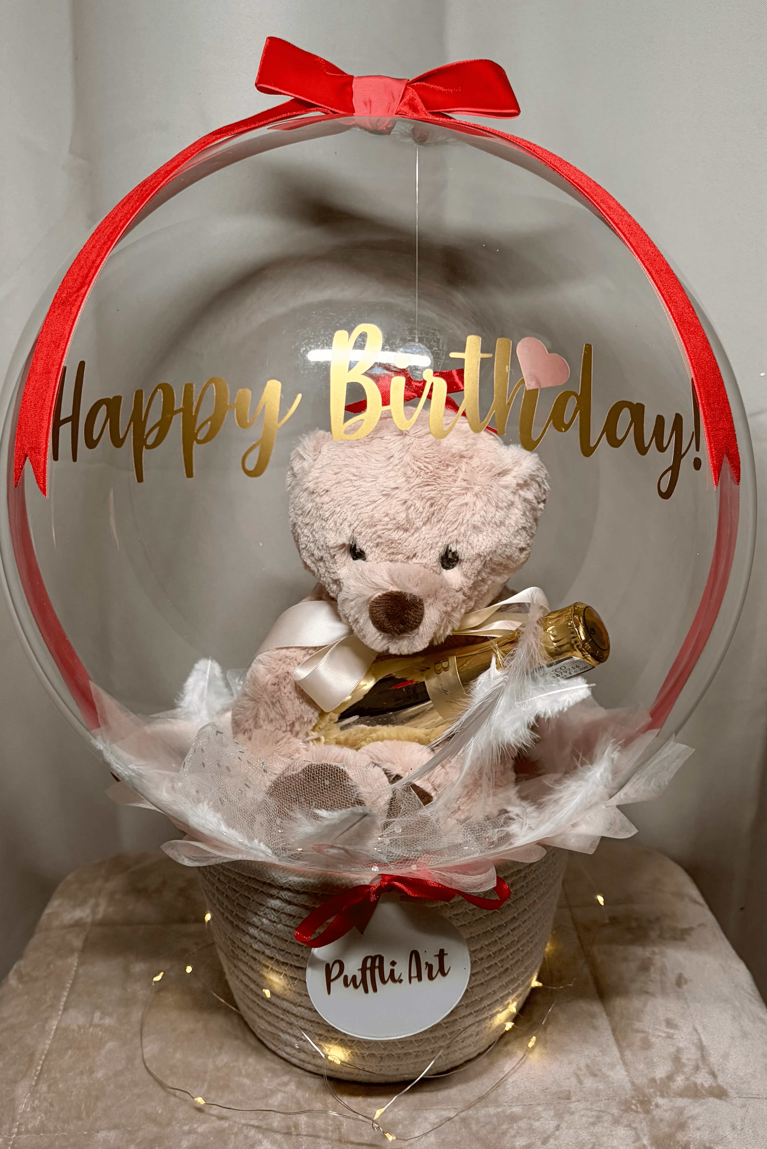 Birthday balloon with teddy bear holding a gold Bottega mini champagne bottle and feathers inside